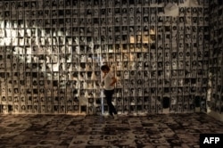 A woman stands among photos taken of human rights victims during martial law, displayed at an experiential museum inside a military camp in Manila on February 24, 2016, ahead of the 30th anniversary of people power that toppled dictator Ferdinand Marcos.