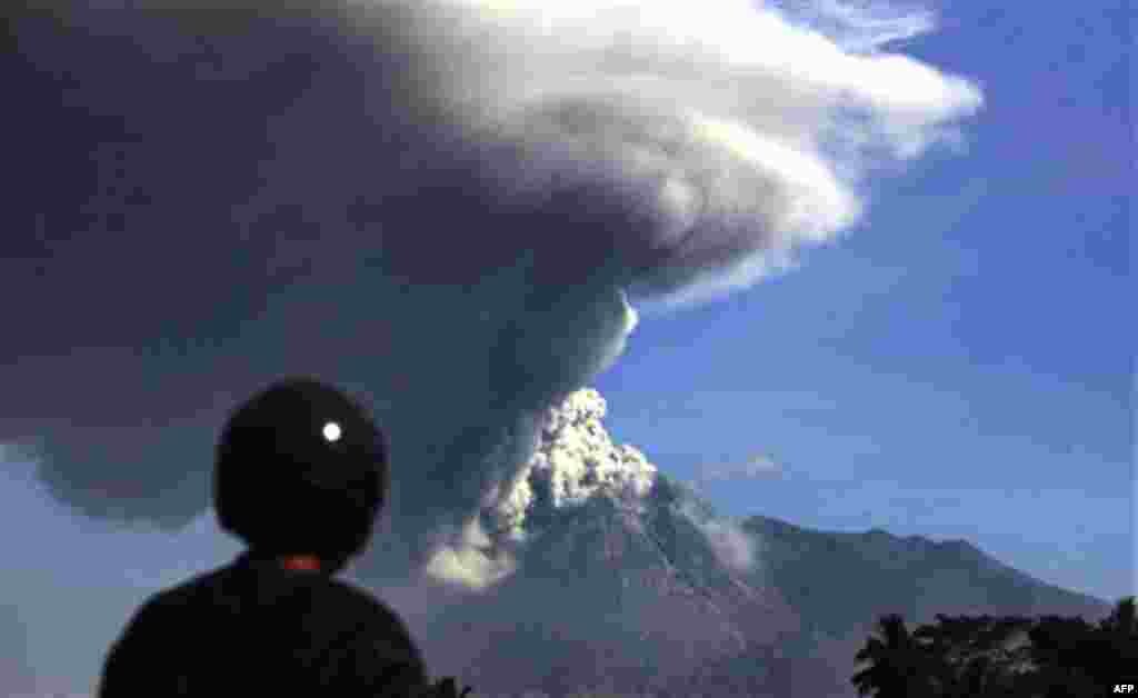 A man watches Mount Merapi spews volcanic material as seen from Argomulyo, Indonesia, Friday, Nov. 12, 2010.(AP Photo/Achmad Ibrahim)