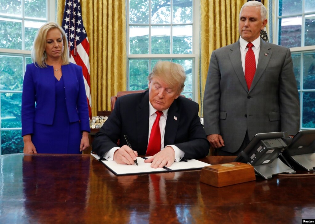 도널드 트럼프 대통령이 20일, 마이크 펜스 부통령과 커스텐 닐슨 국토안보부 장관이 지켜보는 가운데 불법 이민자 가족의 격리를 막는 행정명령에 서명하고 있다.