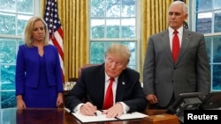 Perezida Donald Trump arikumwe n'icegera ciwe Mike Pence hamwe na sekreteri w'intwaro mu gihugu Kirstjen Nielsen asinya itegeko rihagarika gutandukanya abana n'abavyeyi binjira baciye kubiri n'amategeko.