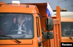Russian President Vladimir Putin drives a Kamaz dump truck during a ceremony opening the Kerch Strait Bridge, which connects the Russian mainland with territorially disputed Crimea, May 15, 2018.