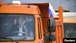 Presiden Rusia Vladimir Putin mengendari truk dalam upacara peresmian Jembatan Selat Kerch yang menghubungkan daratan Rusia dengan wilayah Krimea yang masih dalam sengketa, 15 Mei 2018.