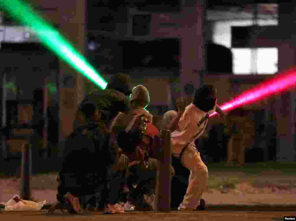 Laser beams are shot through the air as demonstrators hurl rocks during a protest demanding government action to tackle poverty, police violence and inequalities in healthcare and education systems, in Bogota, Colombia, May 10, 2021.