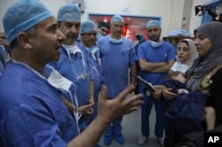 In this Monday, March 5, 2018 photo, Jordanian and Italian doctors brief Syrian refugee Sara al-Matoura before performing surgery on her one-year-old daughter Eman at a hospital in Amman Jordan.