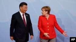FILE - Chinese President Xi Jinping is greeted by German Chancellor Angela Merkel after arriving at the G-20 Summit, July 7, 2017, in Hamburg. 