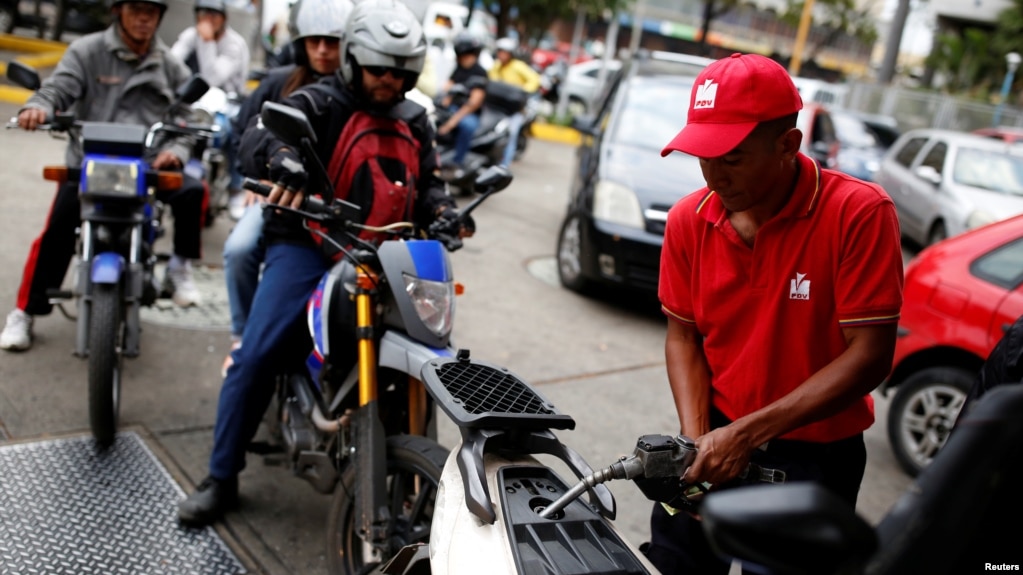 A gas station worker pumps gas into a motorcycle as people wait in line to fill the tanks of their vehicles at a gas station of the state oil company PDVSA in Caracas, Venezuela, March 22, 2017. 