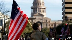 ARSIP – Seorang anggota Pramuka AS membawa bendera AS di sepanjang Congress Avenue menuju Texas State Capitol (2/2/2013). Austin, Texas.