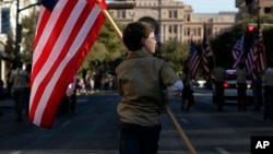 FILE - A Boy Scout carries a U.S. flag up Congress Avenue toward the Texas Capitol, Feb. 2, 2013.