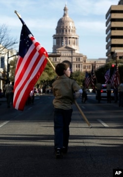 FILE - A Boy Scout carries a U.S. flag up Congress Avenue toward the Texas State Capitol in Austin, Feb. 2, 2013.