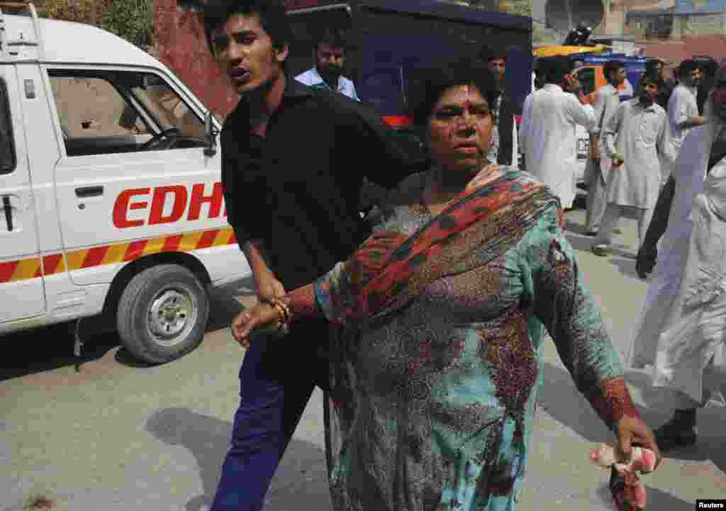 A man helps a woman who was injured in a church suicide blast, as she arrives at the Lady Reading Hospital for treatment, in Peshawar, Pakistan, Sept. 22, 2013. 