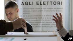 FILE - A voter casts his ballot in a polling station, in Rome.