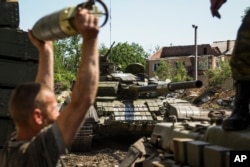 FILE - A pro-Russia rebel loads shells onto a tank near Donetsk, eastern Ukraine, June 12, 2015.