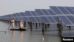 FILE - Employees examine solar panels installed at a pond in Lianyungang, Jiangsu Province, China, March 16, 2016. Efforts are underway to take the green financing agenda beyond clean energy projects.