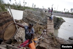 People use a handmade ladder after the bridge has been destroyed by Hurricane Matthew in Chantal, Haiti, Oct. 7, 2016.