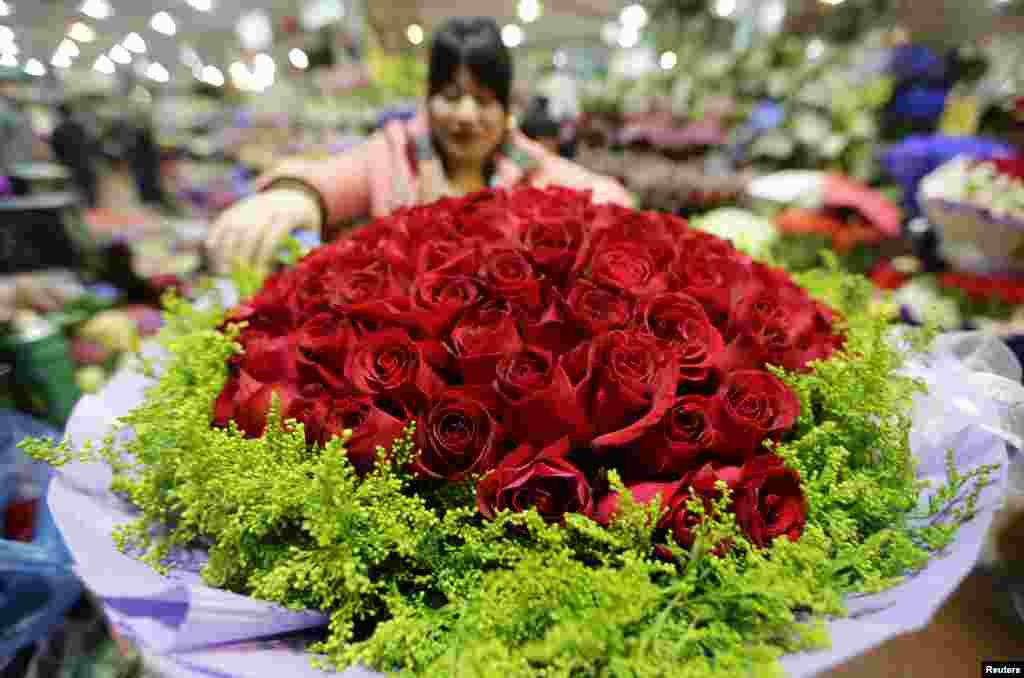 A woman packs a bouquet of 99 roses for the upcoming Valentine&#39;s Day at a market in Beijing, China.