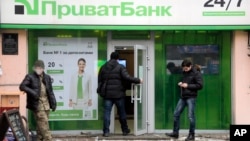 A client enters PrivatBank as others stand by in the center of Kyiv, Ukraine, Dec. 19, 2016.