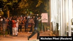 Un manifestant casse la vitrine d'un magasin non loin du troisième commissariat de la police de Minneapolis, au Minnesota, le 27 mai 2020. (Photo REUTERS/Nicholas )