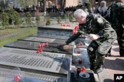 FILE - A Ukrainian lays flowers on the tombstone with his relative's name, during a requiem ceremony to commemorate victims of the Chernobyl tragedy, in Ukraine's capital Kiev, Ukraine, April 26, 2015.