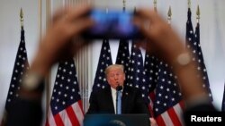 FILE - A reporter uses his mobile phone to record U.S. President Donald Trump at a news conference in New York, Sept. 26, 2018. A presidential wireless emergency alert system is planned for 2:18 p.m. EDT Wednesday. Some people are upset that they cannot opt out of the test, while others fear Trump will abuse the system.