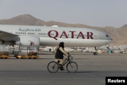 FILE - A Taliban soldier patrols on a bike in front of a Qatar Airways flight at the international airport in Kabul, Afghanistan, Sept. 10, 2021. (West Asia News Agency via Reuters)