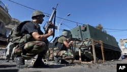 FILE - Lebanese army soldiers open fire during clashes with Islamic militants in the northern port city of Tripoli, Oct. 26, 2014.