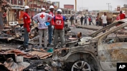 FILE - Red Cross personnel search for remains at the site of one of Tuesday's car bombs in Jos, Nigeria, May 21, 2014.