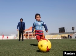 FILE - Five-year-old Murtaza Ahmadi wears a shirt of Barcelona's star Lionel Messi made of a plastic bag as he plays soccer at the Afghan Football Federation headquarters in Kabul, Afghanistan, Feb. 2, 2016.