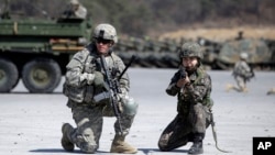 FILE - A U.S. Army soldier and a South Korean Army soldier take their position during joint military exercises between South Korea and the United States in Pocheon, north of Seoul, South Korea, March 25, 2015.