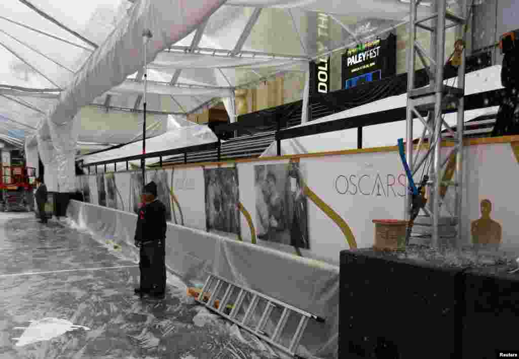 A worker keeps rainwater from pooling on a temporary roof over the red carpet as preparations for the 86th Academy Awards continue in the rain outside The Dolby Theatre in Hollywood, California, Feb. 28, 2014.&nbsp;