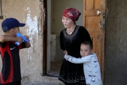 Alif Baqytali hugs his mother, Gulnar Omirzakh, at their new home in Shonzhy, Kazakhstan.