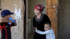 Alif Baqytali hugs his mother, Gulnar Omirzakh, at their new home in Shonzhy, Kazakhstan.