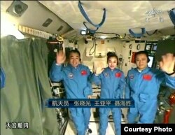 FILE - In this image taken June 20, 2013, and made from CCTV, Chinese astronauts from left, Zhang Xiaoguang, Wang Yaping and Nie Haisheng, wave during a live broadcast from onboard the Tiangong 1 prototype space station.