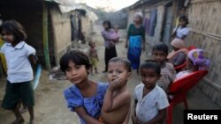 FILE - A Rohingya refugee girl carries a baby inside a refugee camp in Sitwe, in the state of Rakhine, Myanmar, March 4, 2017. 