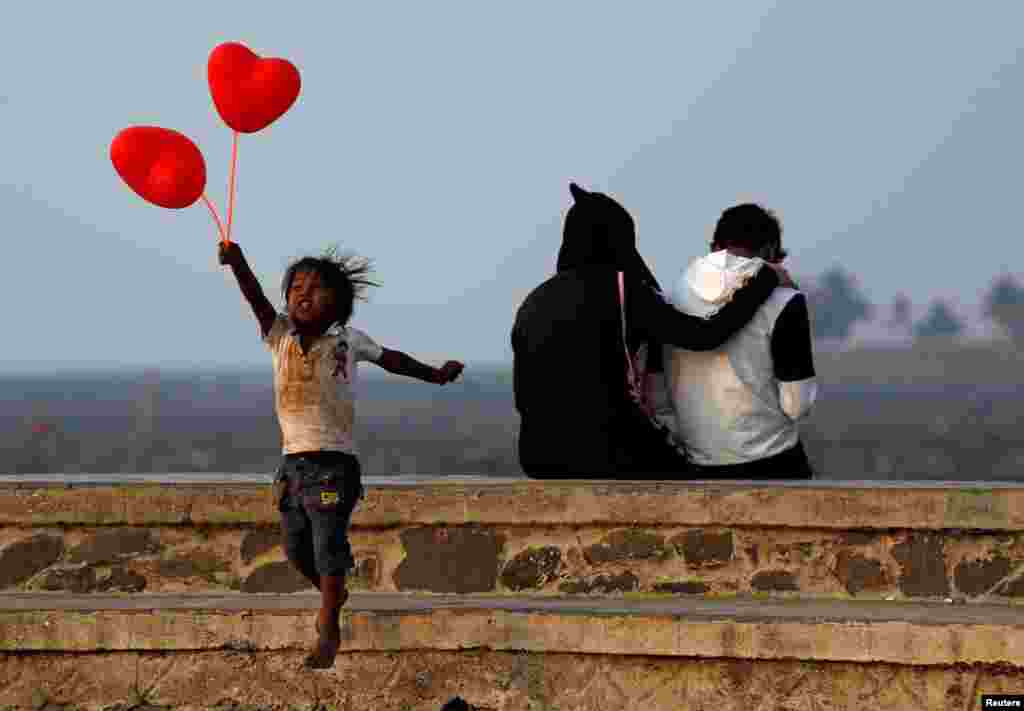 A child jumps from a promenade after attempting to sell heart-shaped balloons to a couple on Valentine&#39;s Day in Mumbai, India.