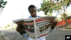 A Kenyan looks at a newspaper a day after the country's presidential election, at a roadside stall in Nairobi, Kenya, March 5, 2013.