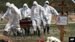 俄罗斯圣彼得堡的丧葬业人员身穿防护服掩埋新冠病毒死者，死者的亲友远远地遥望他们的亲人在新冠患者死去后被指定的区域下葬。（2020年5月15日）