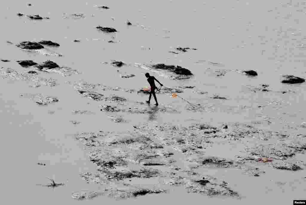 A man pulls a magnet to find coins thrown by devotees as religious offerings into the river Ganges in Allahabad, India.