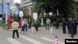 Para pengunjuk rasa memegang spanduk, potret almarhum pemimpin Tiongkok Mao Zedong, dan bendera Tiongkok di dekat barisan polisi yang berjaga di luar kantor pusat surat kabar Southern Weekly di Guangzhou, propinsi Guangdong. (8/1)