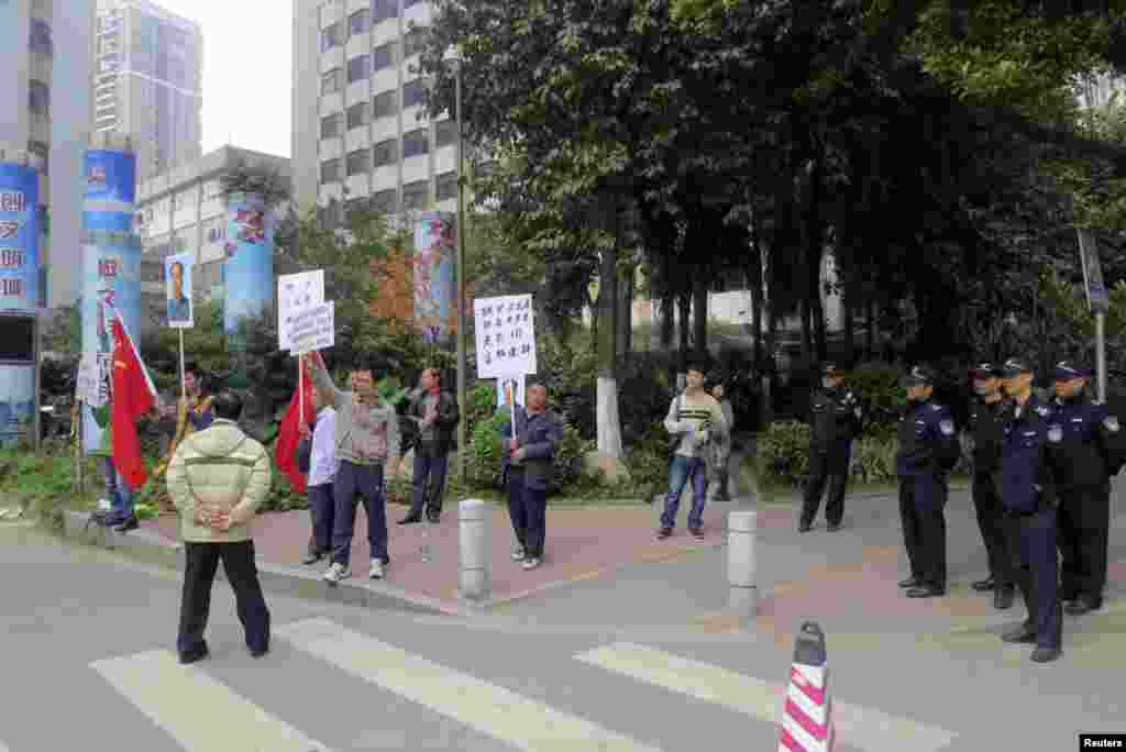 2013年1月8日，示威抗议者在南方周末总部外面的执勤警察旁边举着旗帜和已故毛泽东的遗像