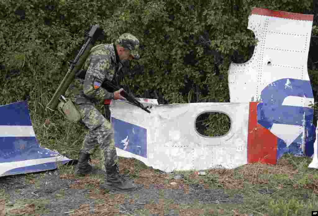 A Pro-Russian rebel looks at pieces of the Malaysia Airlines Flight 17 plane near village of Rozsypne, eastern Ukraine, Sept. 9, 2014.