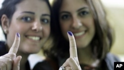 Egyptian women show their inked fingers after voting in Cairo, Egypt, Monday, Nov. 28, 2011