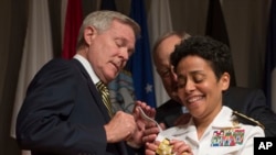 Adm. Michelle Howard, right, lends a hand to Secretary of the Navy Ray Mabus as he and Wayne Cowles, Howard's husband, put four-star shoulder boards on Howard's service white uniform during her promotion ceremony at the Women in Military Service for Ameri