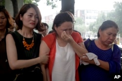 Fan Lili (c) the wife of imprisoned activist Gou Hongguo, is escorted by Li Wenzuz (L) the wife of imprisoned lawyer Wang Quanzhang, and another woman as they stage a protest outside the Tianjin No. 2 Intermediate People's Court in Tianjin, China.