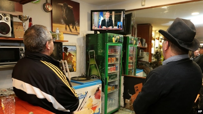 La gente ve al presidente francés Emmanuel Macron durante un discurso televisado a la nación, en Hendaya, suroeste de Francia, el lunes 10 de diciembre de 2018.