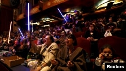 FILE - Moviegoers cheer and wave lightsabers at "Star Wars: The Force Awakens" at the TCL Chinese Theatre in Hollywood, California, Dec. 17, 2015.