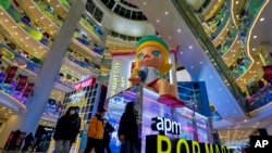 北京一個購物中心內，戴口罩的消費者站在玩具製造商POP Mart的顯示屏前（2020年12月9日）。