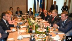 FILE - German Chancellor Angela Merkel, 2nd left, French President Emmanuel Macron, left, and Ukraine's President Petro Poroshenko, 2nd right, meet for talks in Aachen, Germany, May 10, 2018.