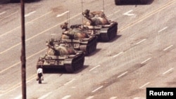 FILE - A man stands in front of a convoy of tanks in the Avenue of Eternal Peace in Beijing, China, June 5, 1989. 