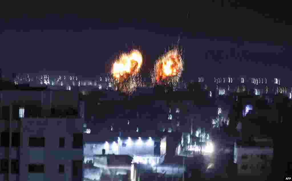 Explosions light-up the night sky above buildings in Gaza City as Israeli forces shell the Palestinian enclave.