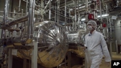 FILE - Wearing protective clothes, an Iranian security person walks through the Uranium Conversion Facility just outside the city of Isfahan, 410 kilometers, south of the capital Tehran, Iran, March 30, 2005.